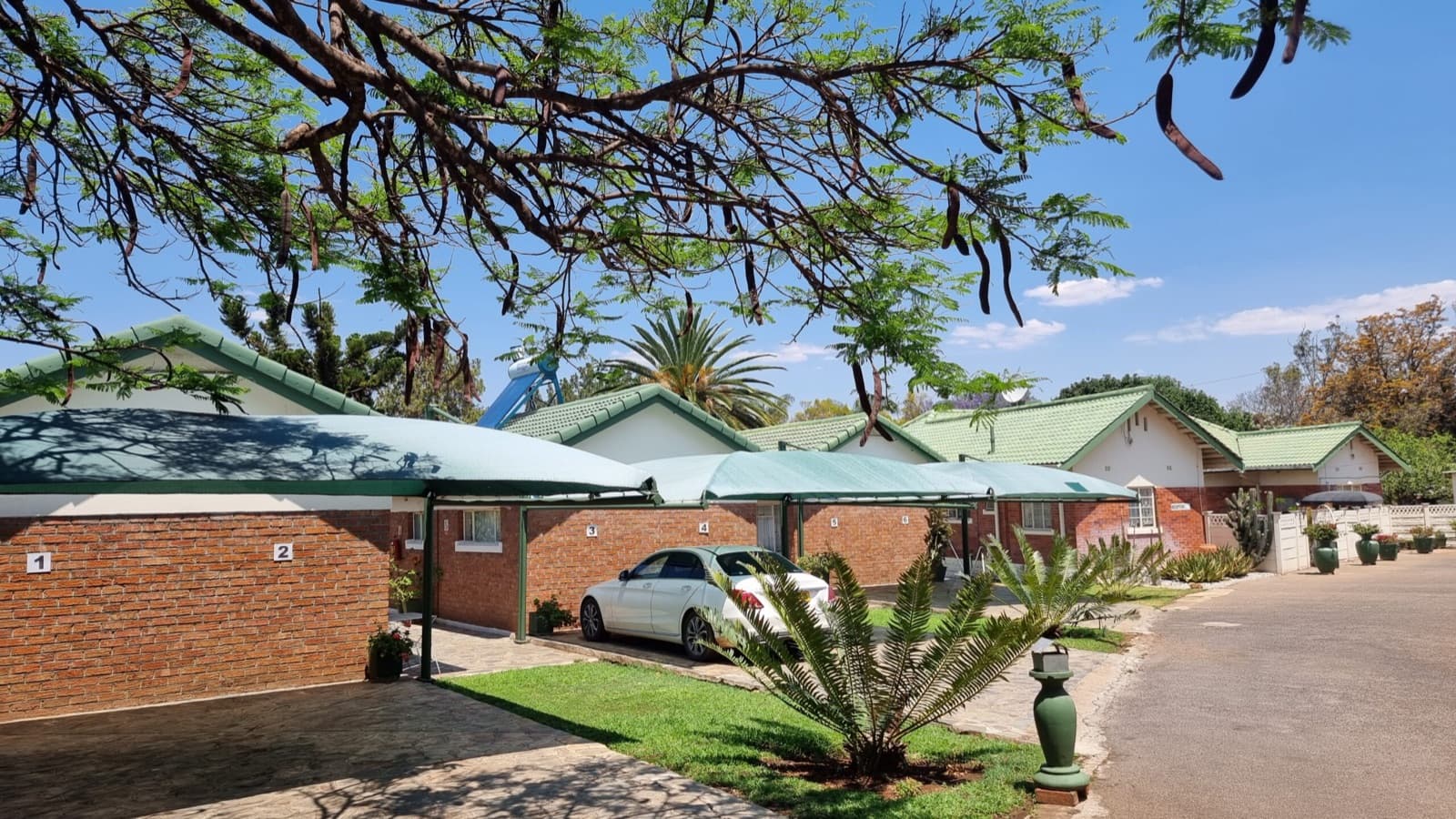 Brick chalets with green roofs set among trees at Villa Thabiso